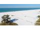 Expansive aerial view of the beach with white sand, clear blue water, and scattered beachgoers on a sunny day at 1110 Villagio Cir # 103, Sarasota, FL 34237