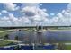 A scenic aerial view of a large lake with a modern, multi-story building complex, palm trees and blue skies at 1110 Villagio Cir # 103, Sarasota, FL 34237