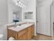 Bright bathroom features a vanity with wood cabinets, tan countertop, a large mirror, and a view to a bedroom at 1110 Villagio Cir # 103, Sarasota, FL 34237