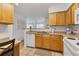 Well-lit kitchen with wood cabinets, white appliances, and tile flooring creating a welcoming atmosphere at 1110 Villagio Cir # 103, Sarasota, FL 34237