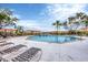 Community pool surrounded by lounge chairs, lush landscaping, and well-maintained buildings under a blue sky at 1110 Villagio Cir # 103, Sarasota, FL 34237