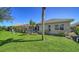 Lush backyard featuring a screened-in pool area, well-manicured lawn, and mature palm trees at 129 Wayforest Dr, Venice, FL 34292