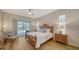 Bright main bedroom with a ceiling fan, light wood floors and sliding glass doors to the screened patio at 129 Wayforest Dr, Venice, FL 34292