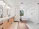 Bright bathroom with dual vanity, standalone tub, and glass enclosed shower, all with modern fixtures at 15101 Rawls Rd, Sarasota, FL 34240