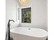 Elegant standalone bathtub with black fixtures positioned beneath a window for a relaxing, bright bathing experience at 15101 Rawls Rd, Sarasota, FL 34240