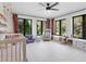 Bright Bedroom with plush carpet, rocking chair, crib, and large windows with exterior views at 15101 Rawls Rd, Sarasota, FL 34240