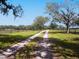 Gravel driveway lined with trees and a wooden fence, leading into the property at 15101 Rawls Rd, Sarasota, FL 34240