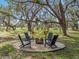 Inviting outdoor fire pit area with Adirondack chairs and hanging hammocks amongst mature shade trees at 15101 Rawls Rd, Sarasota, FL 34240