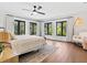 A bright main bedroom features wood floors, a ceiling fan, and windows with lush green views at 15101 Rawls Rd, Sarasota, FL 34240
