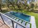 Modern backyard pool surrounded by green grass and mature trees at 15101 Rawls Rd, Sarasota, FL 34240