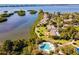 This aerial view shows waterfront condos, pool, and community paths surrounded by water and lush vegetation at 1519 Pelican Point Dr # 288, Sarasota, FL 34231