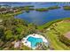 Aerial view of the community pool surrounded by lush landscaping and the beautiful bay at 1519 Pelican Point Dr # 288, Sarasota, FL 34231