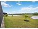 Spacious backyard with green grass, palm trees, and a waterfront view at 17519 Polo Trl, Lakewood Ranch, FL 34211