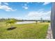 Large grassy backyard with waterfront view, featuring lush green grass and young palm trees at 17519 Polo Trl, Lakewood Ranch, FL 34211