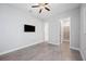 Modern bedroom features wood-look tile flooring, ceiling fan, and wall-mounted TV at 17519 Polo Trl, Lakewood Ranch, FL 34211