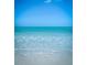 Calm beach scene with gentle waves washing ashore and a clear blue sky creating a serene coastal setting at 1771 Ringling Blvd # 902, Sarasota, FL 34236