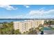 Multi-story residential building with white trim, balconies, and tennis courts, situated near a scenic body of water at 280 Hidden Bay Dr # 202, Osprey, FL 34229