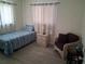 Bright bedroom features wood-look flooring, a twin bed with blue bedding, and a cozy seating area at 3013 Yarmouth W Dr, Bradenton, FL 34205