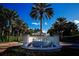 Welcoming Bird Key entrance features a beautiful water fountain, lush tropical landscaping, and a glimpse of neighborhood beyond at 329 Bird Key Dr, Sarasota, FL 34236
