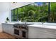 Well-lit kitchen featuring stainless steel appliances, modern cabinetry, and a large window view of tropical foliage at 329 Bird Key Dr, Sarasota, FL 34236