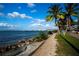 Scenic view of Sarasota Bay with a waterfront path, blue skies, palm trees, and cityscape in the distance at 329 Bird Key Dr, Sarasota, FL 34236