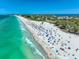 Panoramic aerial beach view showcasing sparkling turquoise waters and white sands filled with people enjoying beach activities and sunshine at 3608 54Th W Dr # 102, Bradenton, FL 34210