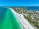Aerial view showing a sandy beach with a lifeguard tower, people enjoying sun and sand, and neighborhood views at 3608 54Th W Dr # 102, Bradenton, FL 34210