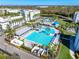 Aerial view of a resort-style swimming pool with modern lounging area, surrounded by palm trees and manicured landscaping at 3608 54Th W Dr # 102, Bradenton, FL 34210