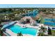 Aerial view of a community pool, clubhouse, tennis court, and lake surrounded by palm trees and landscaping at 4509 Halls Mill Xing, Ellenton, FL 34222