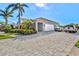 Home exterior featuring a paver driveway leading to a two-car garage with lush landscaping at 556 Regatta Way, Bradenton, FL 34208