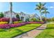 Landscaped front yard with vibrant flowers, palm trees, and a brick walkway leading to the front door at 556 Regatta Way, Bradenton, FL 34208