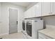 Bright laundry room with white cabinets, gray walls, tile flooring, and modern washer and dryer at 556 Regatta Way, Bradenton, FL 34208