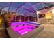 Beautiful outdoor pool area with a spa, a covered patio, lush landscaping, and purple lighting at 556 Regatta Way, Bradenton, FL 34208