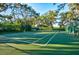 Outdoor tennis court surrounded by lush greenery and mature trees at 556 Regatta Way, Bradenton, FL 34208