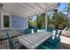 Outdoor seating area with a white table and blue chairs under a pergola near the pool at 709 N Bay Blvd, Anna Maria, FL 34216