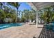 Backyard pool area featuring brick pavers, lush tropical foliage, and white pergola at 709 N Bay Blvd, Anna Maria, FL 34216