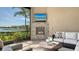 Cozy outdoor seating area with a stone fireplace, TV, and picturesque lake views at 7213 Whittlebury Trl, Lakewood Ranch, FL 34202
