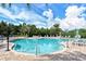 Large community pool surrounded by lush greenery, palm trees, and comfortable lounge chairs at 7213 Whittlebury Trl, Lakewood Ranch, FL 34202
