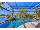 Sparkling pool with lush tropical landscaping, rock features, and a clear view of the tranquil waterfront at 7327 Greystone St, Lakewood Ranch, FL 34202