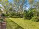 Large, private backyard with mature trees, lush grass, and beautifully landscaped surroundings at 7533 Trillium Blvd, Sarasota, FL 34241