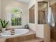 Modern bathroom featuring a soaking tub, tiled shower with glass enclosure, and a window with shutter at 7533 Trillium Blvd, Sarasota, FL 34241