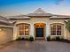 Close up of front entrance featuring a brick driveway, double front doors, and decorative columns under warm lighting at 7533 Trillium Blvd, Sarasota, FL 34241