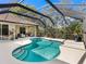 Screened-in pool with a beautiful blue tiled edge and gradual steps, surrounded by lush greenery and backyard patio at 7533 Trillium Blvd, Sarasota, FL 34241