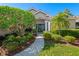Inviting home exterior with a lush front yard, mature trees, and a charming walkway leading to the entrance at 8224 Waterview Blvd, Lakewood Ranch, FL 34202