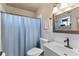 Bathroom with a blue shower curtain, classic white tile, and a well-lit vanity area at 8719 Gaillard Ave, North Port, FL 34287