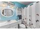 Bright bathroom featuring a vanity, an oval mirror, and a shower with a butterfly-themed curtain at 8719 Gaillard Ave, North Port, FL 34287