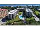 An aerial view of condos, a pool with lounge chairs, and views of the bay in a tranquil community at 8779 Midnight Pass Rd # 406H, Sarasota, FL 34242