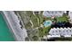 Aerial view showcasing beach access boardwalk, pool, lush landscaping, and beachfront buildings at 8779 Midnight Pass Rd # 406H, Sarasota, FL 34242