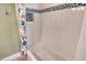 Well-lit bathtub with white tile and glass mosaic accent strip at 8779 Midnight Pass Rd # 406H, Sarasota, FL 34242