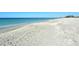 Expansive white sand beach meeting a calm, clear ocean, set against a bright blue sky. Beautiful coastal setting at 8779 Midnight Pass Rd # 406H, Sarasota, FL 34242